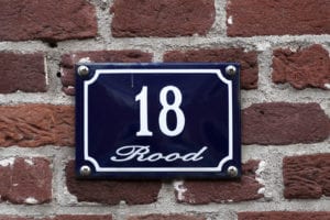 Enameled house number eighteen on a red brick wall